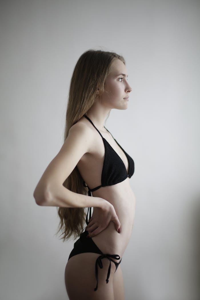 Studio shot of a young woman in black bikini, showing elegance and confidence.