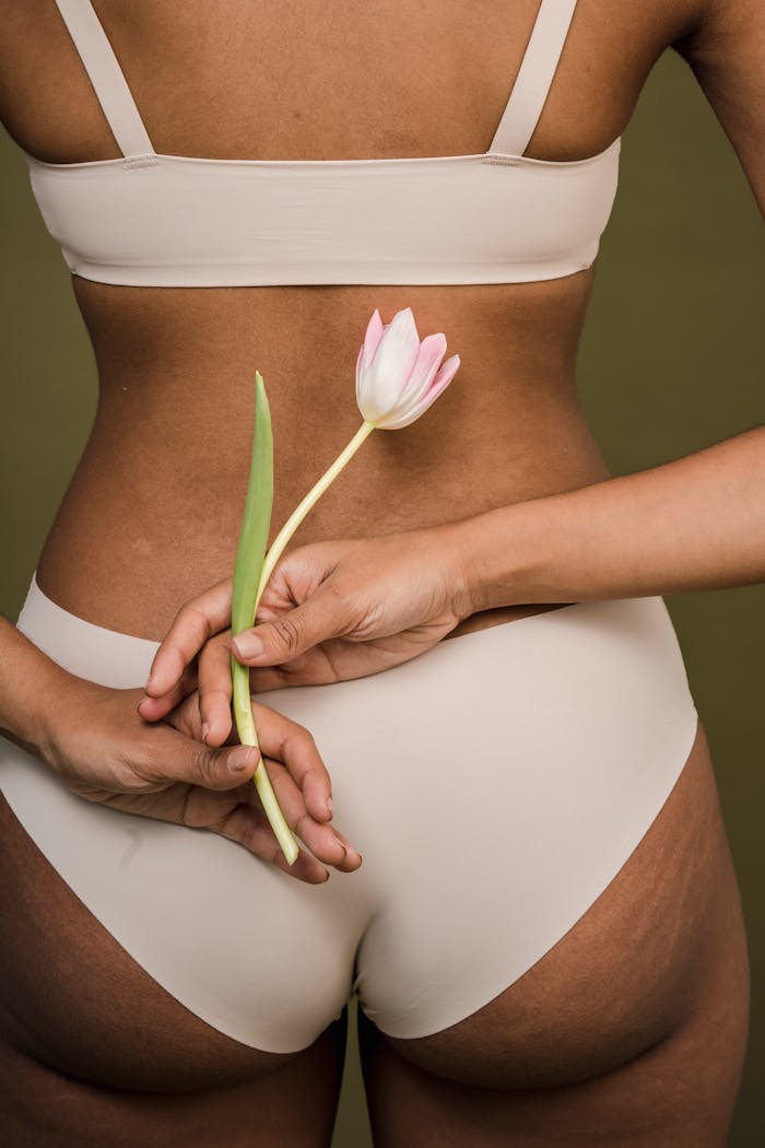 Celebrate body positivity with feminine grace. Woman holding a tulip.